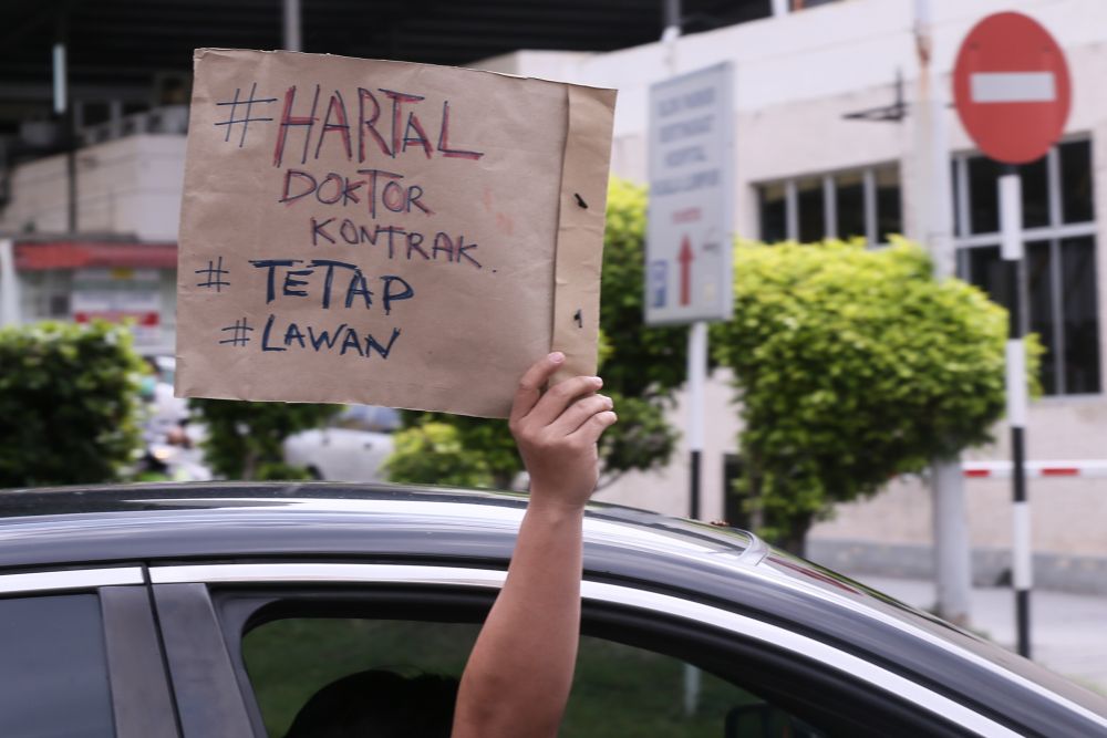 Contract doctors hold aloft placards demanding equal treatment as they go on strike at the Kuala Lumpur Hospital July 26, 2021. — Picture by Ahmad Zamzahuri
