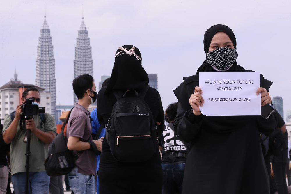 Contract doctors hold aloft placards demanding equal treatment as they go on strike at the Kuala Lumpur Hospital July 26, 2021. — Picture by Ahmad Zamzahuri