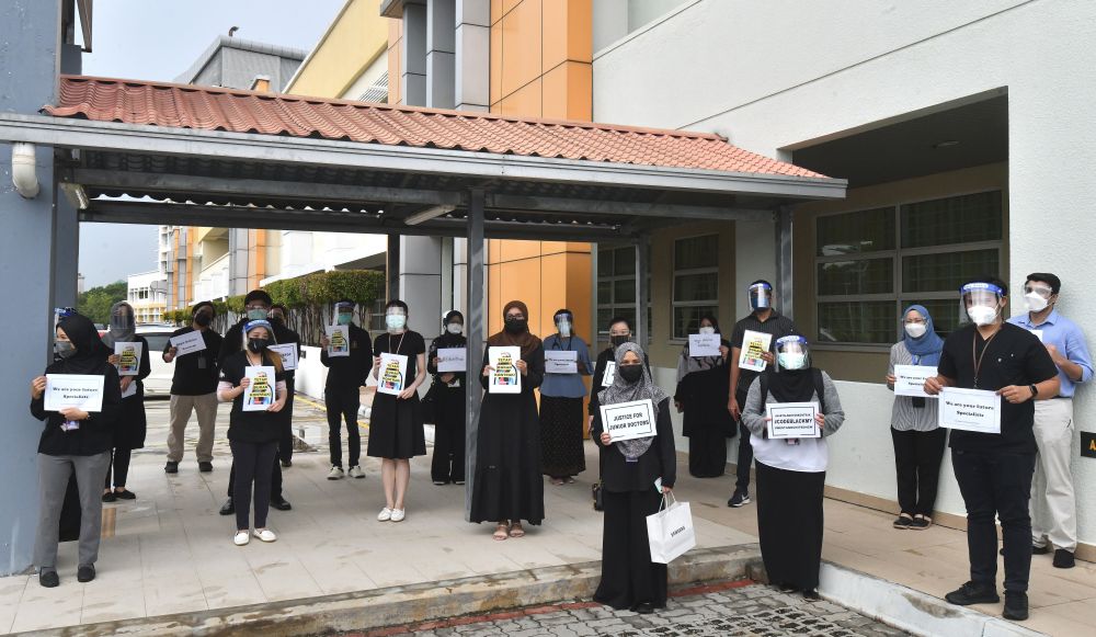 Contract doctors hold aloft placards demanding equal treatment as they go on strike at the Putrajaya Hospital July 26, 2021. 