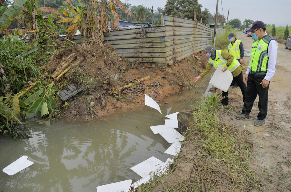 Johor DOE director Dr Mohd Famey Yusoff and agency officers placing oil absorbent pads on water from a drain near a premise in Jalan Besar, Kampung Baru, Sengkang, July 6, 2021. u00e2u20acu201d Bernama pic 