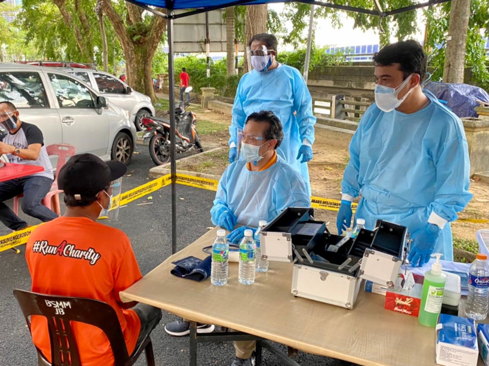 Johor Parti Pejuang Tanah Airu00e2u20acu2122s Dr Zaini Abu Bakar assisted by Johor Pejuang pro-tem deputy chief Nornekman Osman (right) conducting a health check on a homeless person during the Insani Pejuang Johor programme, July 2, 2021. u00e2u20acu201d Picture by Ben Tan
