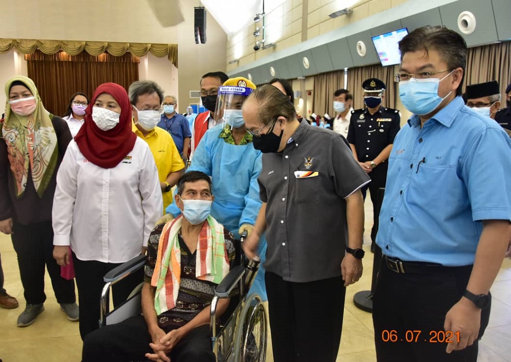 Uggah (second right), with Jamilah (left) and Dr Sim, giving words of encouragement to a man awaiting his turn to be vaccinated. u00e2u20acu201d Borneo Post Online pic