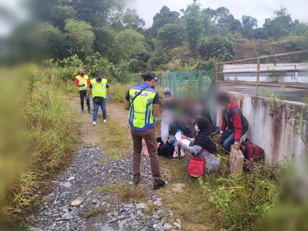 Police personnel questioning the 16 illegal immigrants after intercepting them behind an abandoned factory at Kampung Entubuh, Jalan Serian-Tebedu. u00e2u20acu201d Borneo Post Online pic
