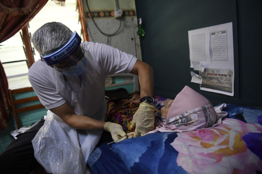 Dr Mohammad Iqbal Omar, head of Mercy Malaysiau00e2u20acu2122s health unit, administers a Covid-19 jab to a bedridden patient in Beranang July 6, 2021. u00e2u20acu201d Bernama pic