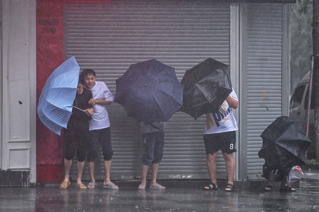 People seek shelter from the rain and wind along a street in Ningbo on July 25, 2021, as Typhoon In-Fa lashes the eastern coast of China. u00e2u20acu201d AFP pic