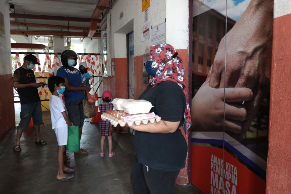 Seri Ayuni is carrying a tray of eggs and some packed food up to her flat in the Kerinchi PPR in Lembah Pantai July 2, 2021. u00e2u20acu201d Picture by Miera Zulyanan
