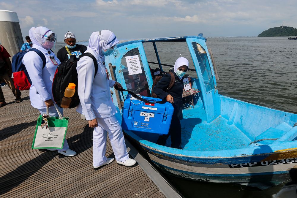 Health personnel board a boat to  Pulau Aman with Covid-19 vaccines as part of the south Seberang Perai health district's mobile outreach programme July 8, 2021. u00e2u20acu201d Picture by Sayuti Zainudin