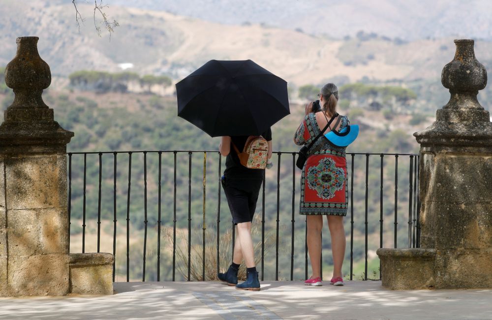 A tourist uses an umbrella to protect himself from the sun from a balcony at Alameda del Tajo park as the summer's first heatwave hits the country, in Ronda, Spain July 10, 2021. u00e2u20acu201d Reuters pic