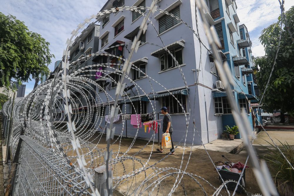 A man walks past barbed wire fencing at the Taman Bukit Angkasa PPR amid the enhanced movement control order in Kuala Lumpur July 11, 2021. u00e2u20acu201d Picture by Yusof Mat Isa
