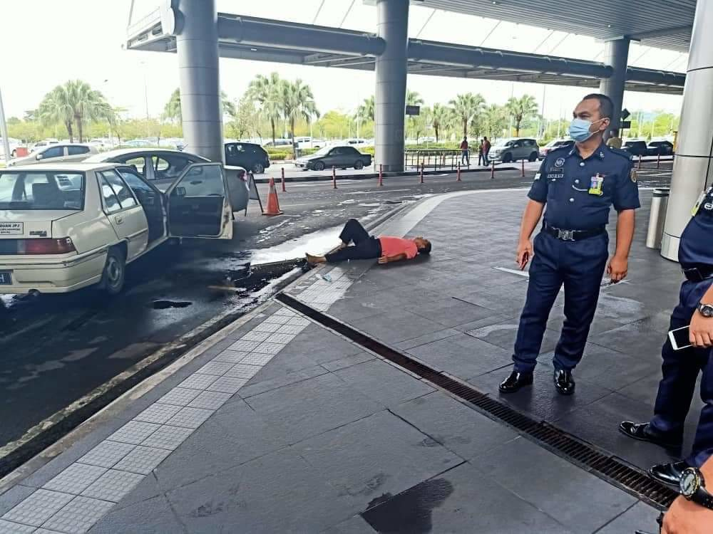 The driver of the vehicle lying down on the pavement after ramming his car into a vehicle at the front of the taxi queue at Kota Kinabalu International Airport, July 19, 2021. 