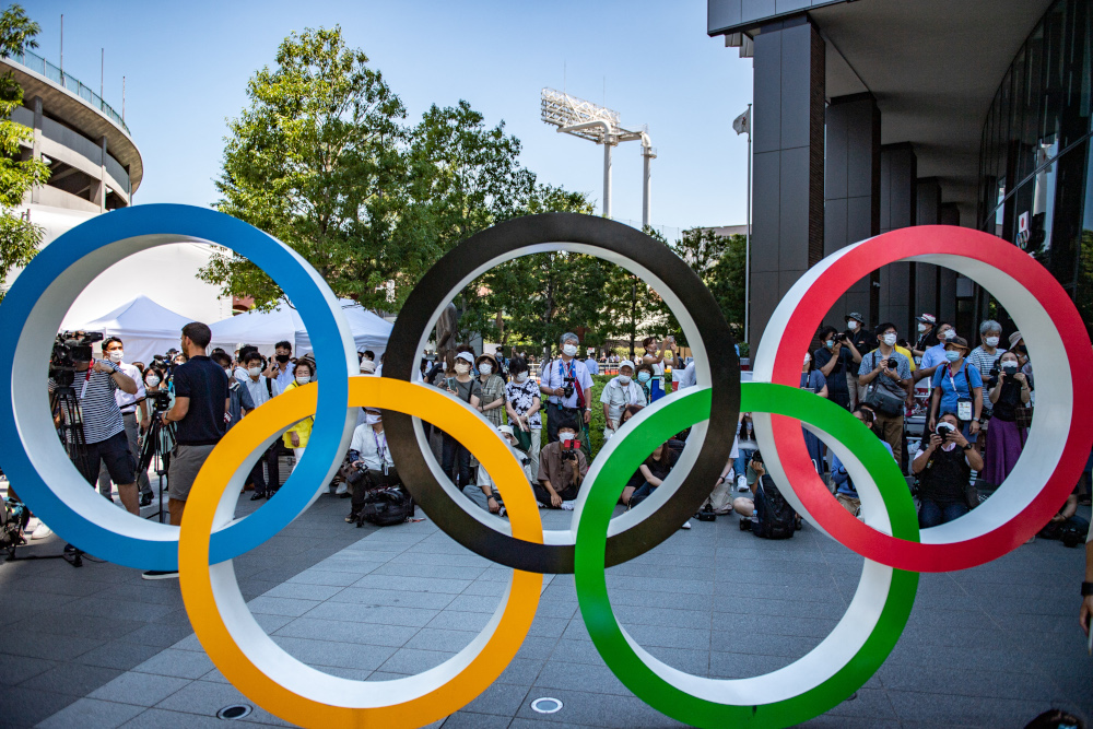People gather near the Olympic Rings to take pictures of the Blue Impulse aerobatic demonstration team of Japan Air Self-Defence Force flying over the Olympic Stadium, during a rehearsal in Tokyo July 21, 2021. u00e2u20acu201d AFP pic 