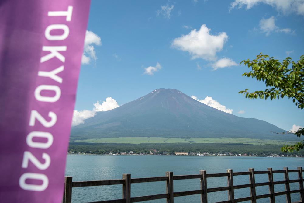 This general view shows Mount Fuji, Japanu00e2u20acu2122s highest mountain at 3,776m seen from Lake Yamanaka, next to a Tokyo 2020 Olympics banner July 19, 2021. u00e2u20acu201d AFP picnn