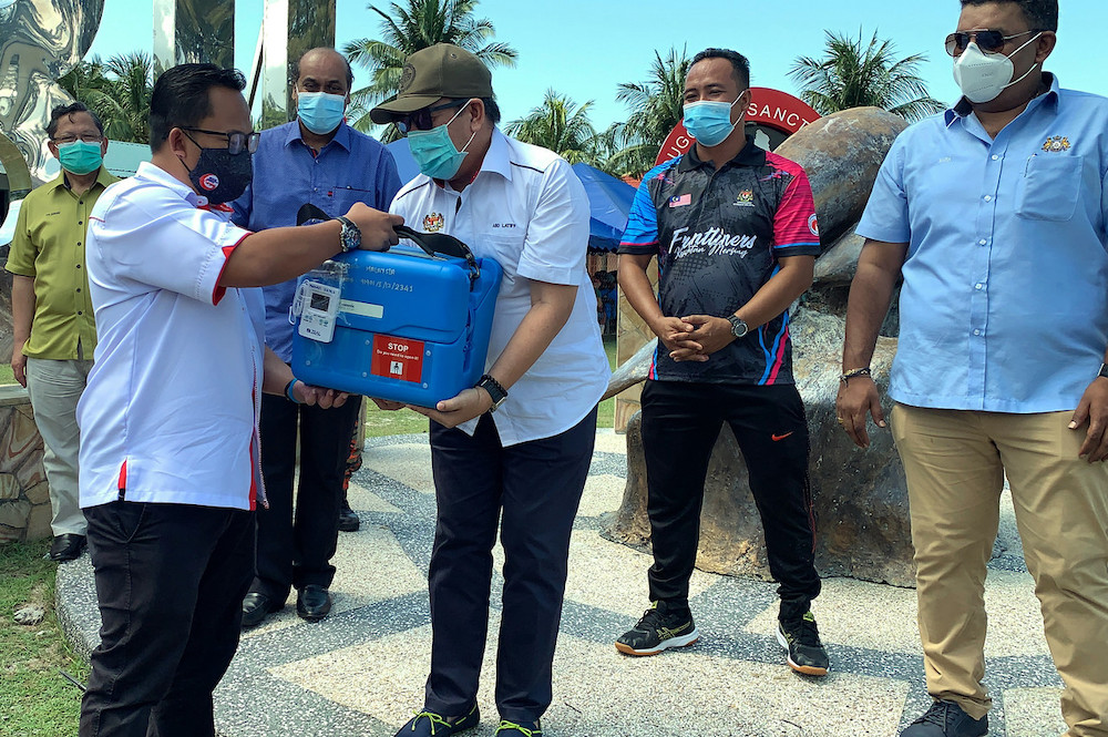 Rural Development Minister Datuk Dr Abdul Latiff Ahmad (right) handing over the Covid-19 vaccine to Mersing District Medical Officer Dr Norzaher Ismail on Pulau Sibu August 7, 2021. u00e2u20acu201d Bernama pic