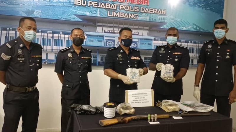 Parum (centre) showing the confiscated syabu. u00e2u20acu201d Borneo Post pic