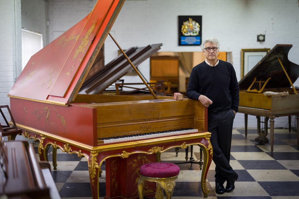 Royal piano restorer David Winston poses for a photograph with an exceptionally rare Pleyel grand piano, made in Paris, dated 1925, at his workshop in Biddenden in south-east England August 6, 2021. u00e2u20acu201d AFP pic