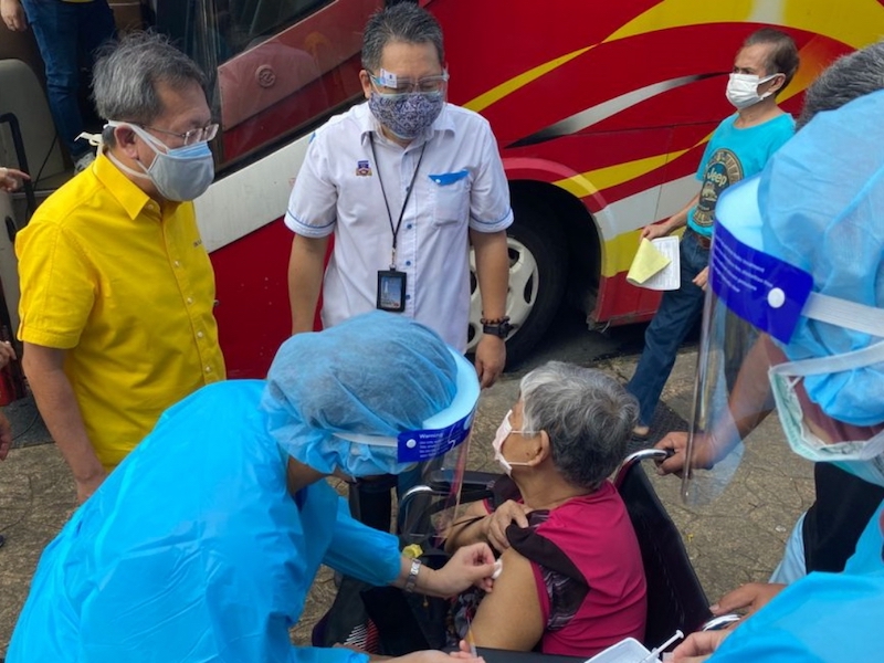Dr Sim and Wee chat with an elderly woman receiving her first jab of the Covid-19 vaccine at the mobile vaccination facility in Kenyalang Park. u00e2u20acu201d Borneo Post pic