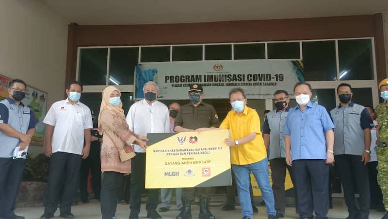 Abang Johari (fifth left), Awang Tengah (fourth left) and others look on as Dr Sim hands over BKSS aid to a recipient.u00e2u20acu201d Picture by Mastura Ismail via Borneo Post