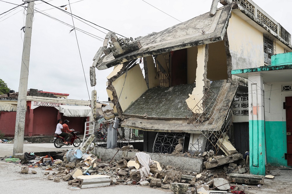 People drive in a motorcycle past damaged home after Saturday's 7.2 magnitude quake, in Les Cayes, Haiti August 17, 2021. u00e2u20acu201d Reuters pic