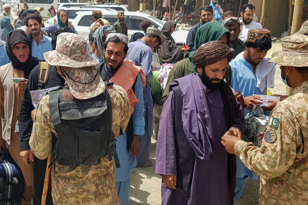 Pakistani soldiers check the documents of stranded Afghan nationals wanting to return to Afghanistan at the Pakistan-Afghanistan border crossing point in Chaman on August 15, 2021. u00e2u20acu201d AFP pic