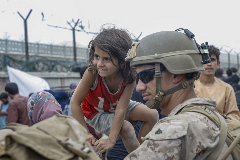 A US Marine with Special Purpose Marine Air-Ground Task Force u00e2u20acu201d Crisis Response u00e2u20acu201d Central Command, waits with a child during an evacuation at Hamid Karzai International Airport, Kabul August 20, 2021. u00e2u20acu201d Picture courtesy of the US Marine Corps via AF