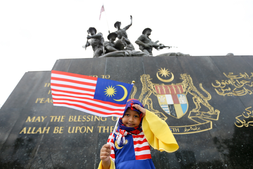 A child poses for a picture while holding a Malaysian flag in conjunction with Merdeka celebrations in Kuala Lumpur August 22, 2021. — Picture by Ahmad Zamzahuri