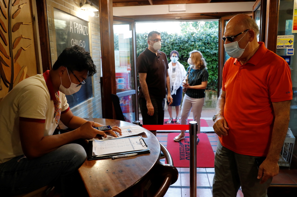 A man has his Green Pass (health pass) checked before entering a pizzeria as Italy brings in tougher restrictions where a proof of immunity will be required to access an array of services and leisure activities, in Rome, Italy, August 6, 2021. u00e2u20acu201d Reuters