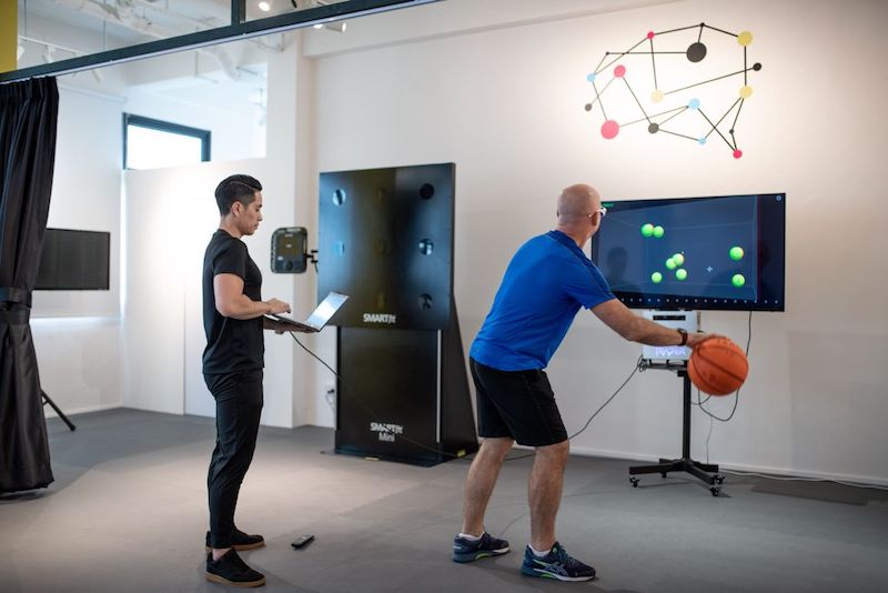A participant (right) hones his multi-tasking skills by tracking objects on a screen while bouncing a basketball. — Sparkd pic via TODAY