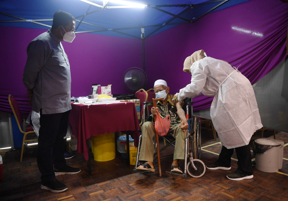 Datuk Seri Abdul Rahman Mohamad watches a senior citizen Abu Kassim Rah receive his Covid-19 vaccination at the Dewan Jubli Perak Sultan Haji Ahmad Shah PPV, August 13, 2021. u00e2u20acu201d Bernama pic 