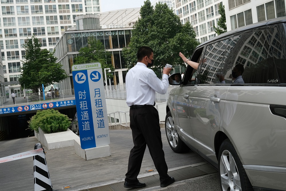 A security guard checks the temperature of a driver at an entrance to a parking lot of an office and commercial compound, following new cases of Covid-19, in Beijing, China August 3, 2021. u00e2u20acu2022 Reuters pic