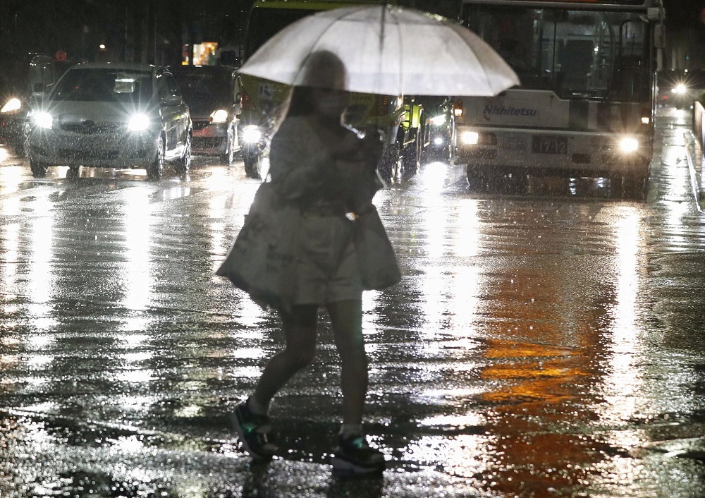 A passerby holding an umbrella walks in the heavy rain in Fukuoka, southwestern Japan August 12, 2021, in this photo taken by Kyodo. u00e2u20acu2022 Kyodo via Reuters