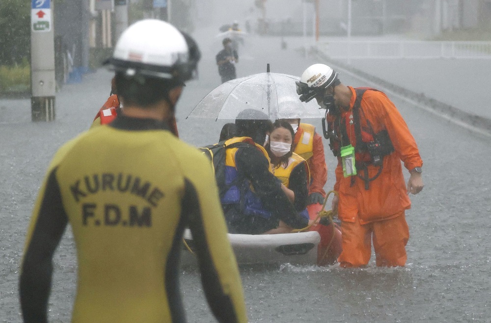 Firefighters transport stranded residents on a boat in a road flooded by heavy rain in Kurume, Fukuoka prefecture, western Japan, August 14, 2021, in this photo taken by Kyodo. u00e2u20acu2022 Kyodo/via Reuters