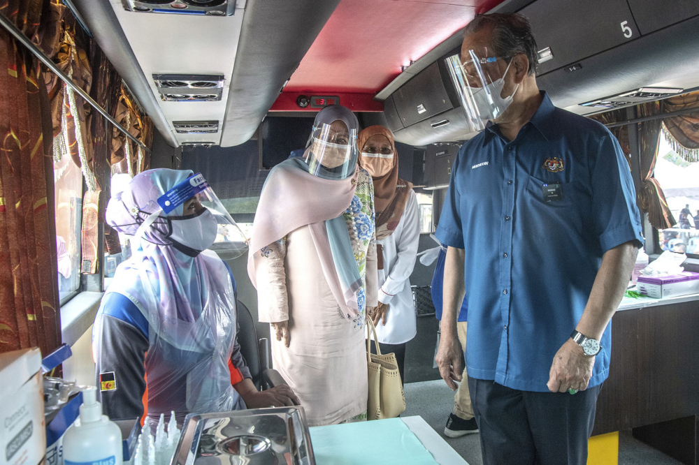Prime Minister Tan Sri Muhyiddin Yassin and his wife Puan Sri Noorainee Abdul chat with health workers during a visit to the vaccination centre at Dataran Felda Batu 27 Pagoh, Johor, August 5, 2021. u00e2u20acu2022 Bernama pic 