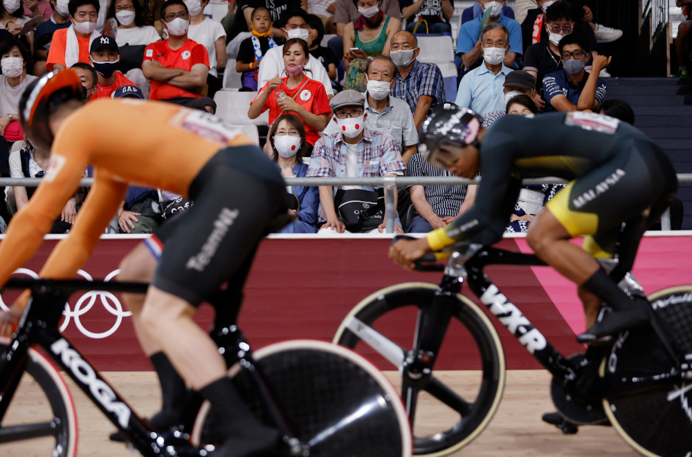 Spectators wearing face masks watch Netherlandsu00e2u20acu2122 Harrie Lavreysen and Malaysiau00e2u20acu2122s Muhammad Shah Firdaus Sahrom as they compete in a heat of the menu00e2u20acu2122s track cycling sprint 1/32 finals during the Tokyo 2020 Olympic Games at Izu Velodrome in Izu, Japan,