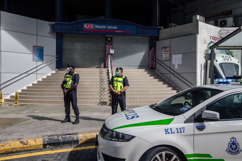 Police personnel stand guard outside the Masjid Jamek LRT station in Kuala Lumpur. 
