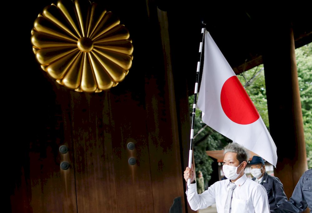 A visitor holds a Japanese flag as he enters Yasukuni Shrine in Tokyo, Japan August 15, 2021. u00e2u20acu201d Reuters pic