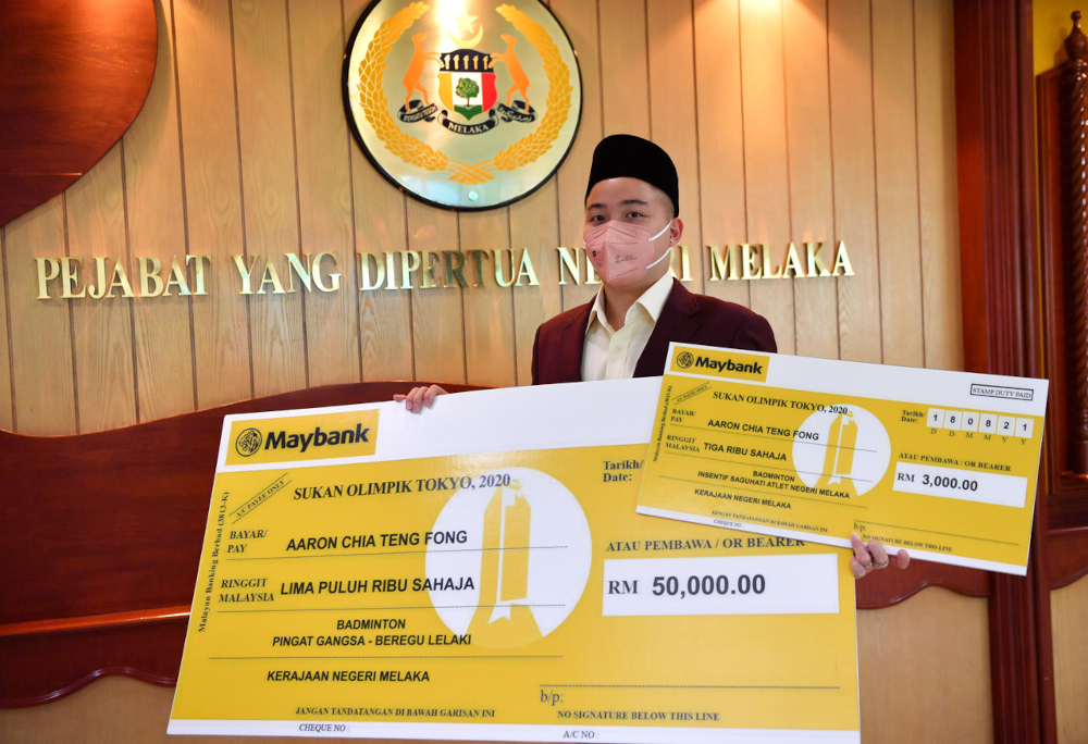 National doubles shuttler Aaron Chia with a RM50,000 replica cheque received for the bronze medal and another RM3,000 as incentive for representing the country at the Tokyo Olympics, in Melaka, August 18, 2021. u00e2u20acu201d Bernama pic 
