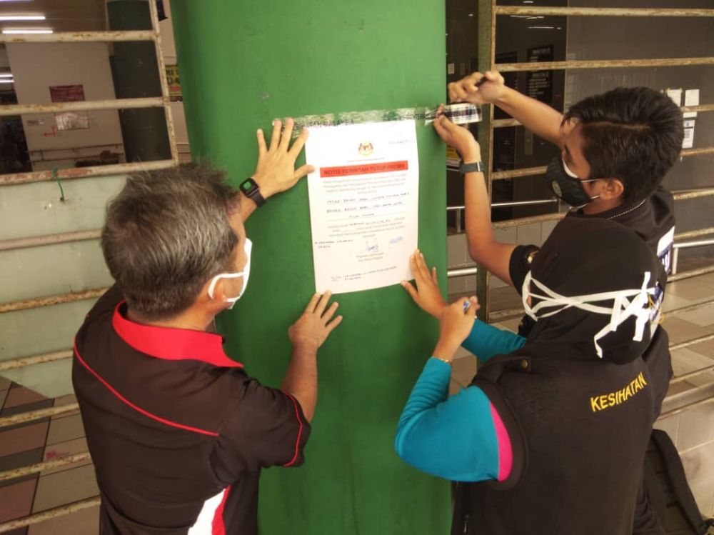 Penang Island City Council personnel, together with mayor Datuk Yew Tung Seang (left), are seen putting up a notice on the closure of the Bayan Baru market August 31, 2021. u00e2u20acu201d Picture courtesy of MBPP