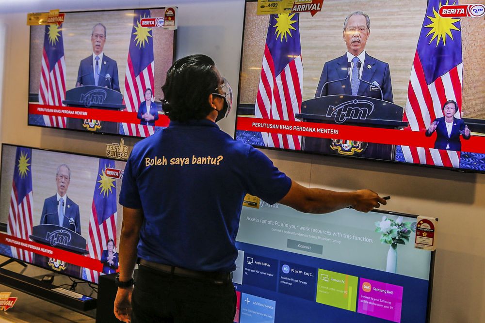 A live telecast of caretaker Prime Minister Tan Sri Muhyiddin Yassinu00e2u20acu2122s speech is played on TV screens at a Courts Mammoth store August 16, 2021. u00e2u20acu201d Picture by Hari Anggara