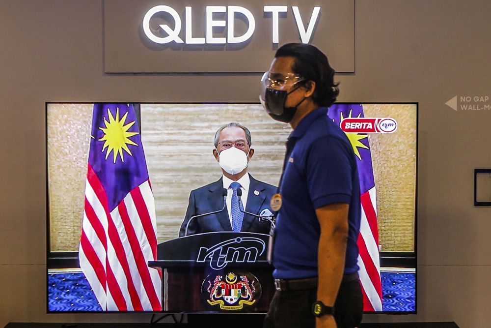 A live telecast of caretaker Prime Minister Tan Sri Muhyiddin Yassinu00e2u20acu2122s speech is played on TV screens at a Courts Mammoth store August 16, 2021. u00e2u20acu201d Picture by Hari Anggara