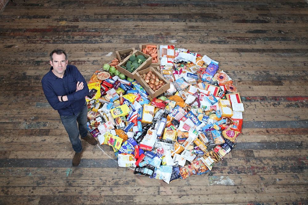 Dr van Tulleken stands next to a pile of food showing the proportion of ultra-processed food compared to fresh food in the average UK diet. — Picture courtesy of BBC Studios