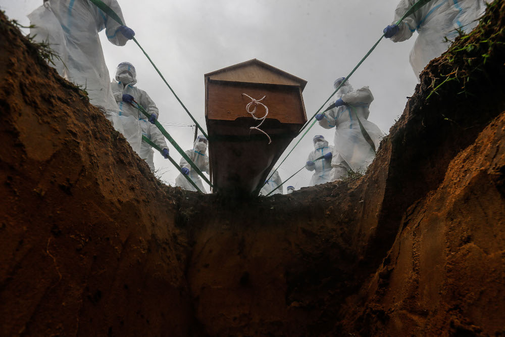 Volunteers place the body of a Covid-19 victim in the grave for burial at Bagan Ajam Muslim Cemetery, August 24, 2021. u00e2u20acu201d Picture by Sayuti Zainudin