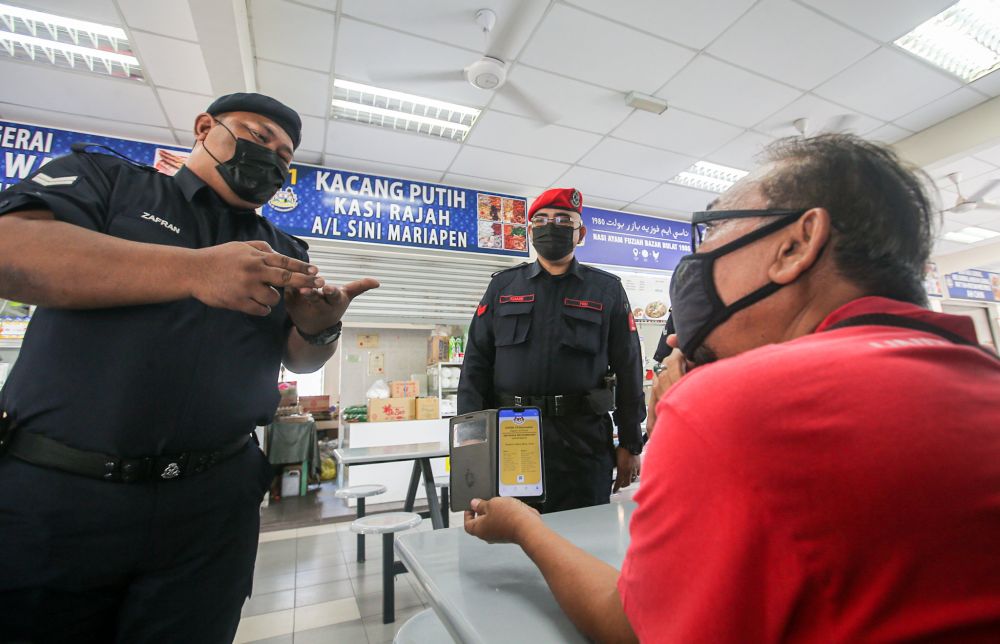 Police personnel conduct checks on patrons at the Dato Sagor food court in Ipoh as dining-in restrictions are lifted in Perak April 10, 2021. u00e2u20acu2022 Picture by Farhan Najib