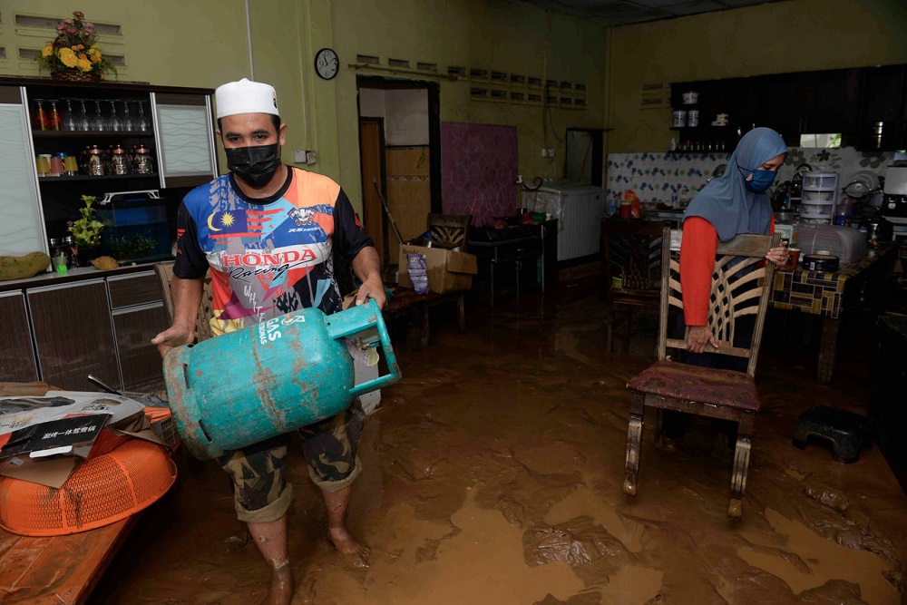A couple are pictured cleaning up their mud-filled house after flood waters recede in Yan, Kedah August 19, 2021. u00e2u20acu2022 Bernama pic
