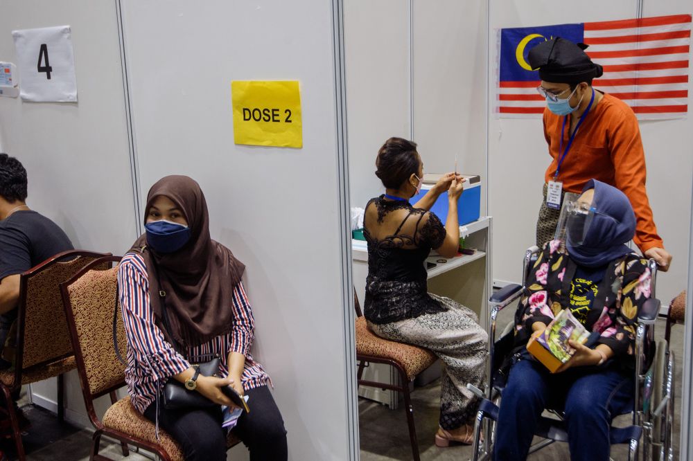 Health workers dressed in traditional attire administer a dose of the Covid-19 vaccine on National Day at the KLCC vaccination centre in Kuala Lumpur August 31, 2021. u00e2u20acu201d Picture by Shazwan Zaidon