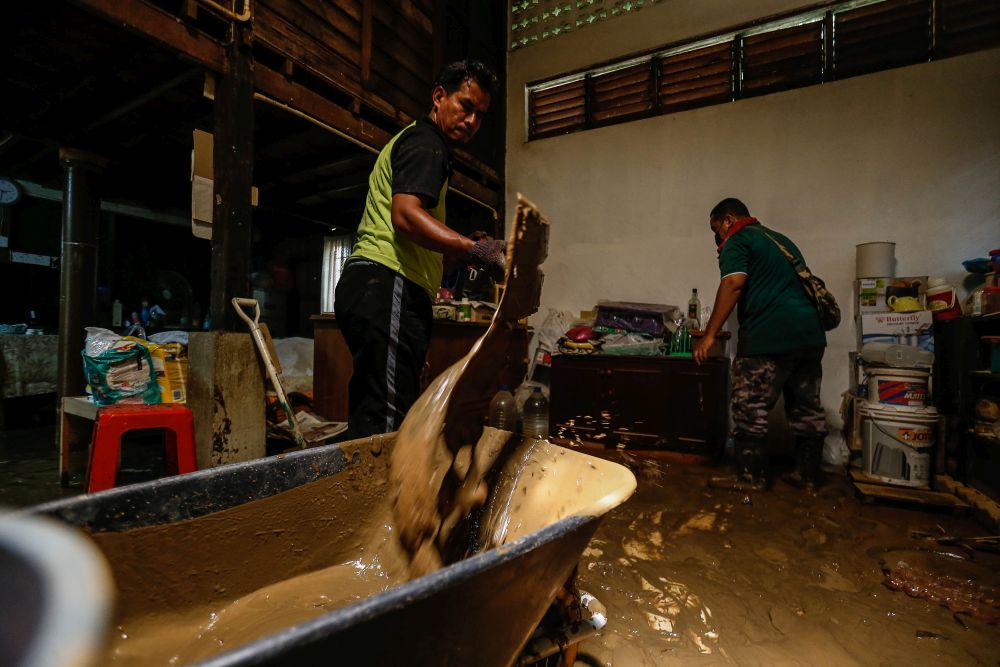 Family members help Ku Masturah clean up her mud-filled house following flash floods in Yan August 25, 2021. — Picture by Sayuti Zainudin