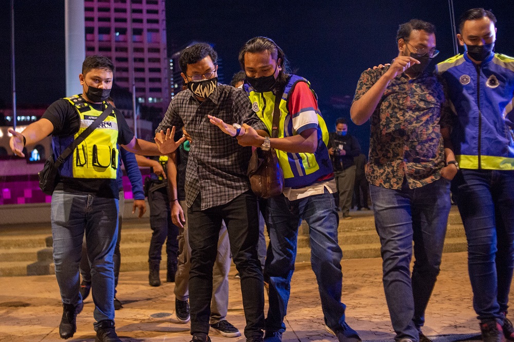 A man is arrested during a candlelight vigil organised by activist movement #Lawan in remembrance of Covid-19 victims at Dataran Merdeka, August 19, 2021. — Picture by Shafwan Zaidon