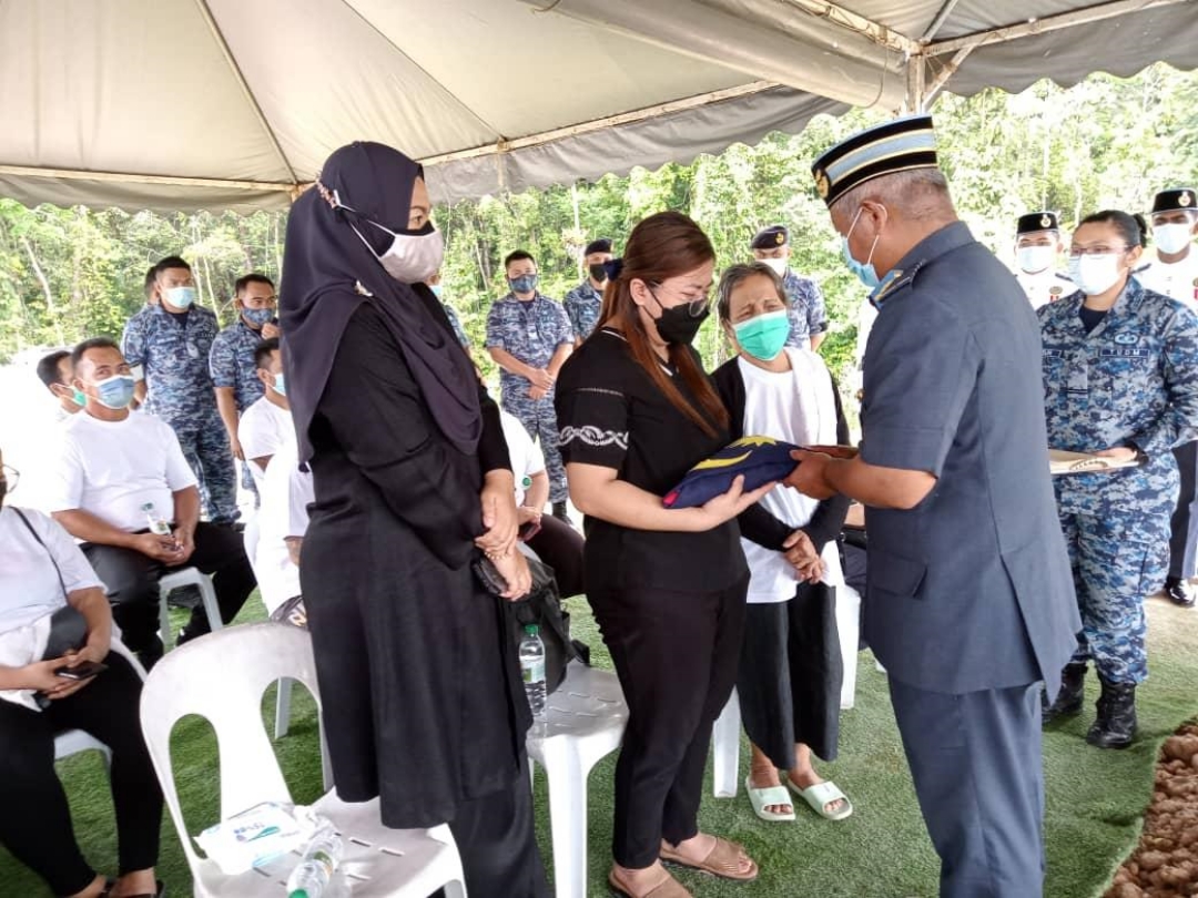 Mohd Azuan (right) presents the Jalur Gemilang to Neslyu00e2u20acu2122s widow Jessica. u00e2u20acu201d Picture via Utusan Borneo