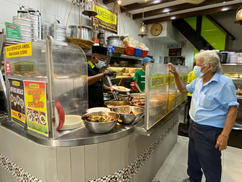 Hameediyah Restaurant director Mohd Riyaaz (left) packing up nasi kandar for a customer to take away. u00e2u20acu2022 Picture by Steven Ooi KE
