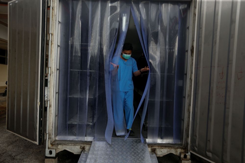 A Kepala Batas Hospital staff walks out of a container which doubles as a morgue in Penang August 20, 2021. u00e2u20acu2022 Picture by Sayuti Zainudin