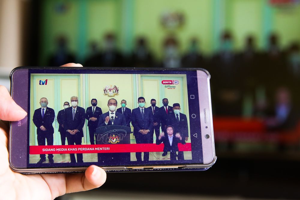 People watch a live telecast of Prime Minister Tan Sri Muhyiddin Yassinu00e2u20acu2122s speech on a smartphone in Kuala Lumpur August 4, 2021. u00e2u20acu201d Picture by Choo Choy May